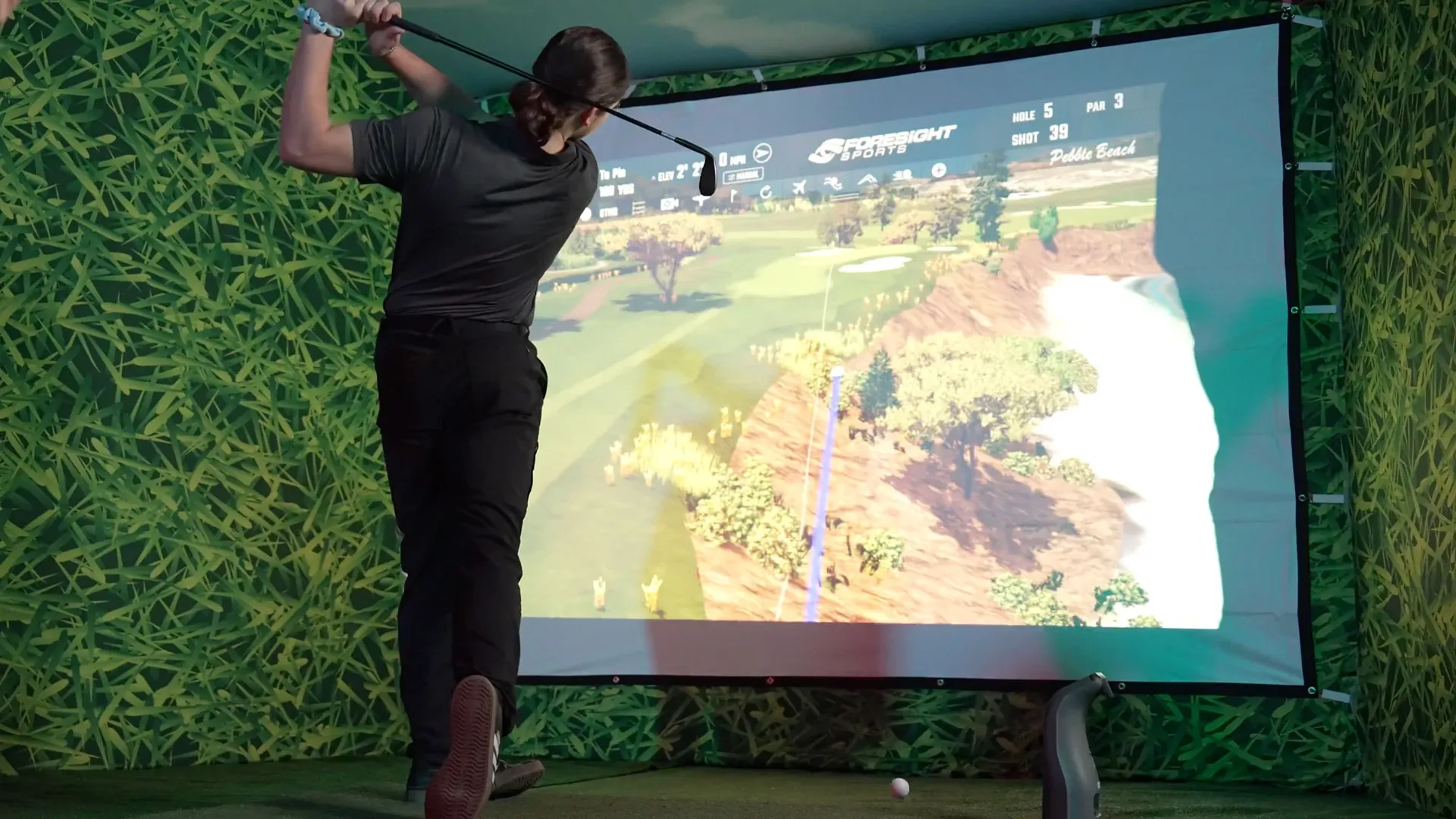 Guest taking a full swing inside a WeGo Golf mobile simulator bay at an event