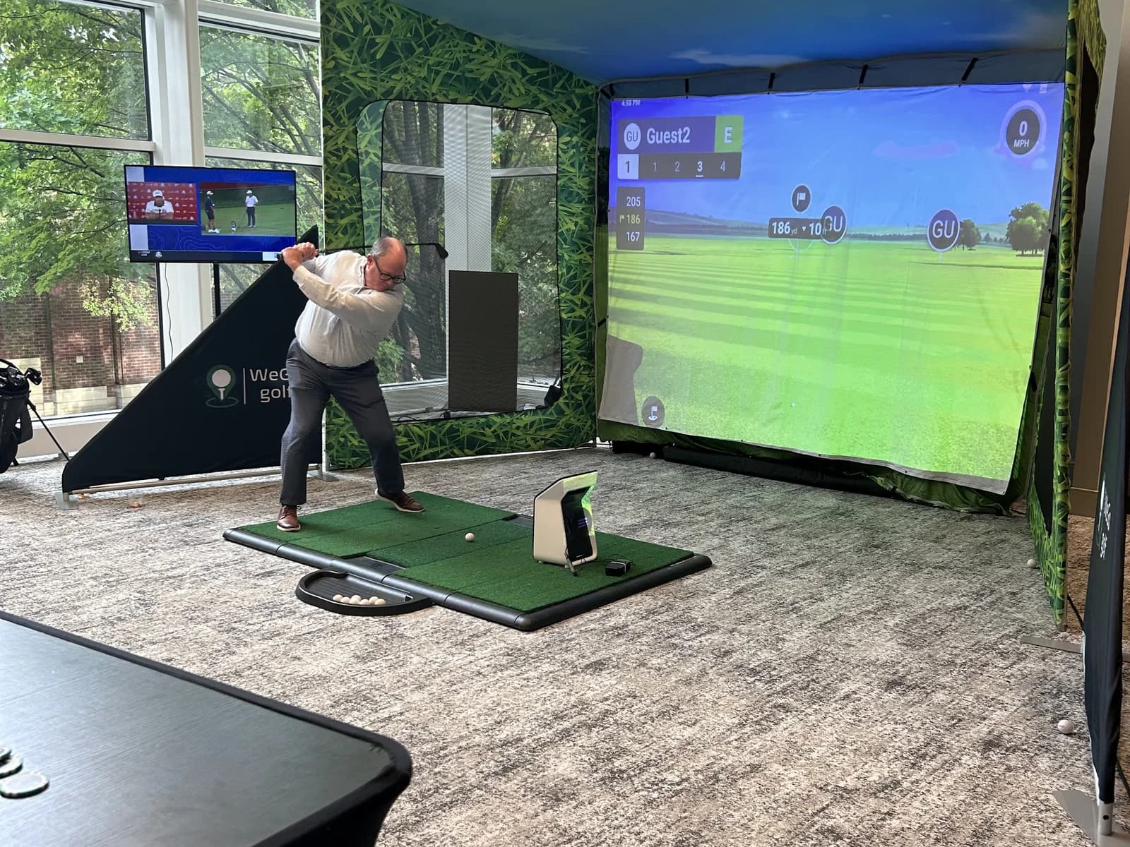 Guest driving a ball in a WeGo Golf bay in a corporate atrium