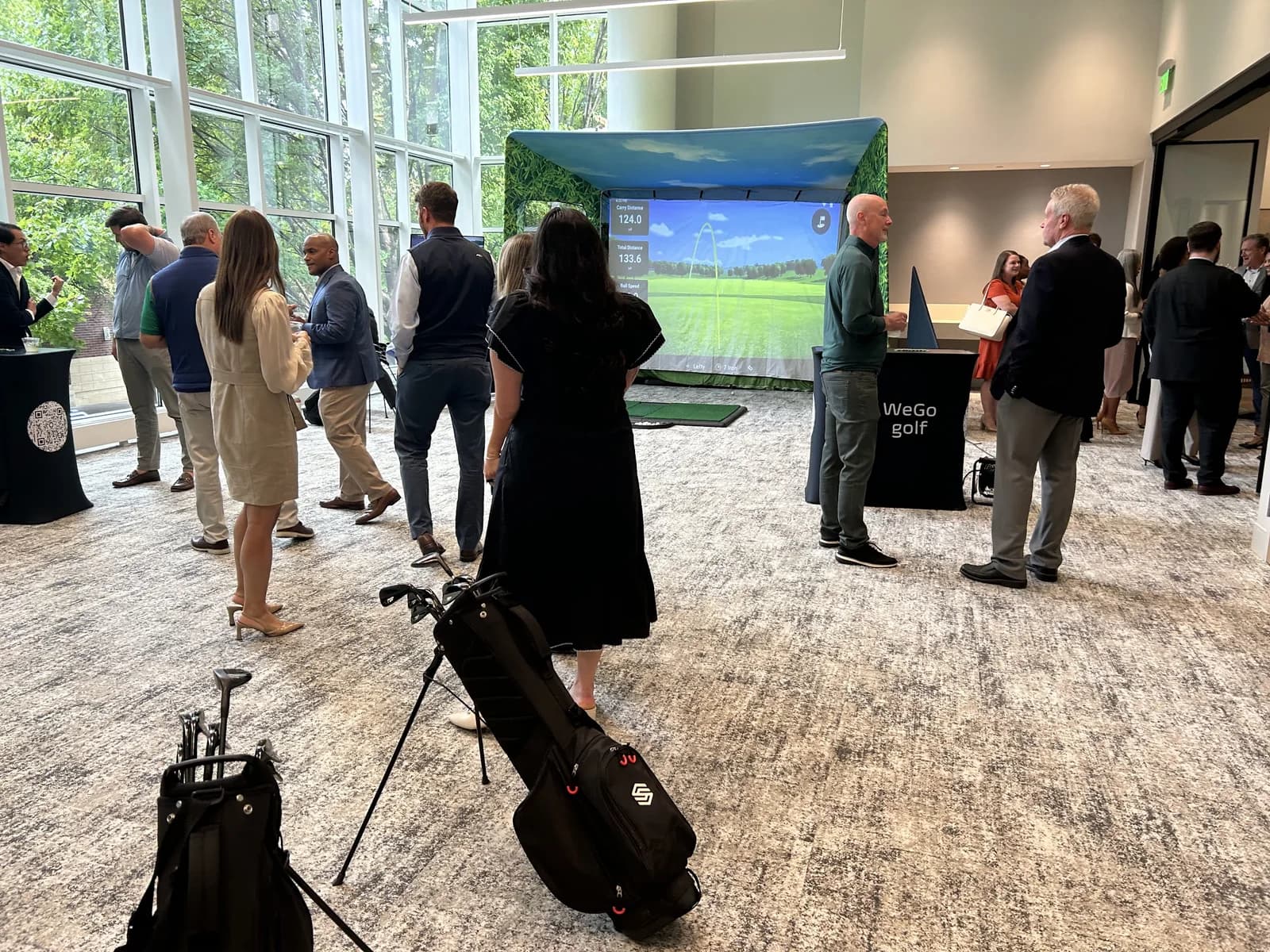 Guests networking around a WeGo Golf simulator at a corporate reception