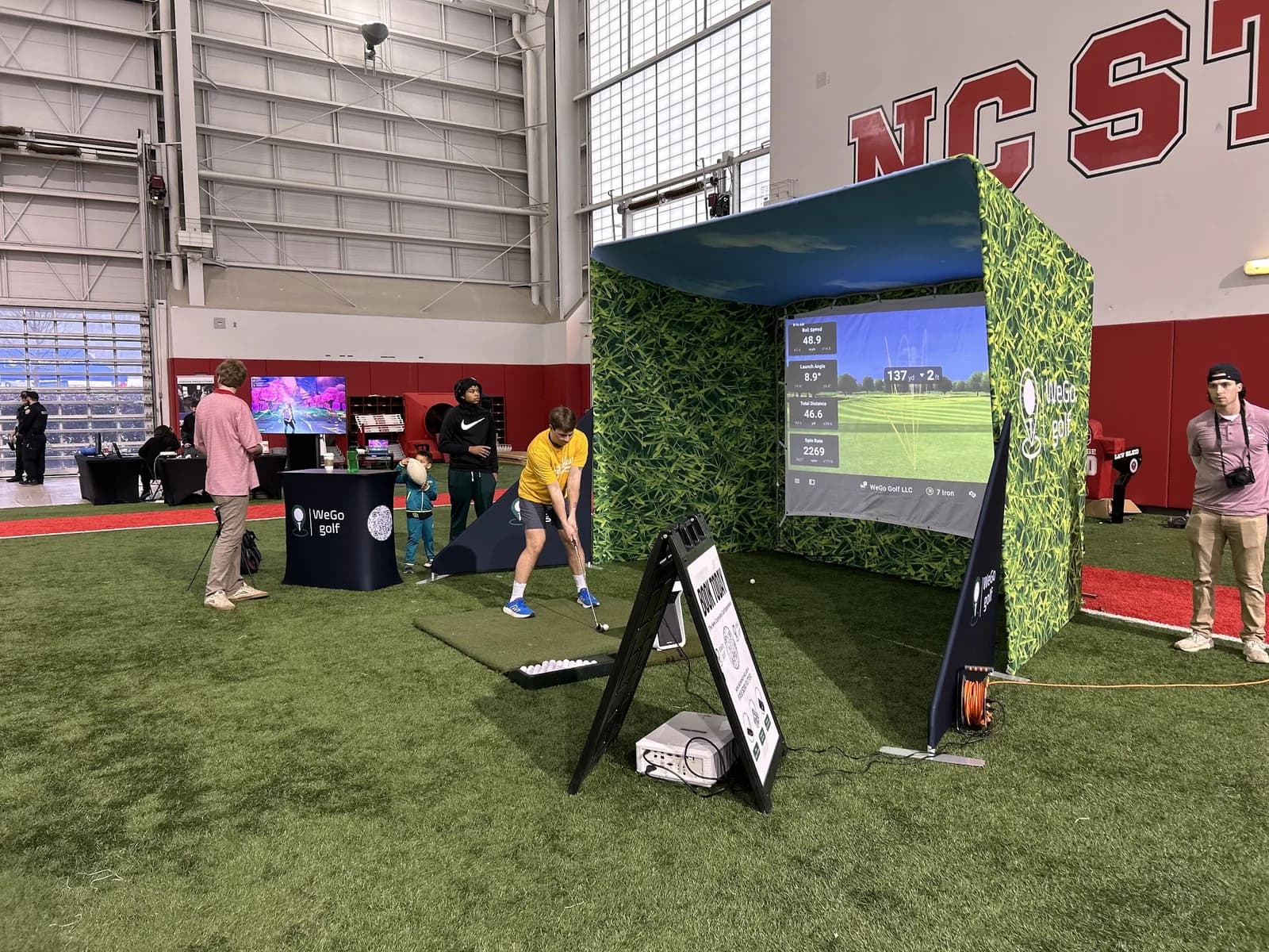 Guest hitting a shot at a WeGo Golf college campus activation