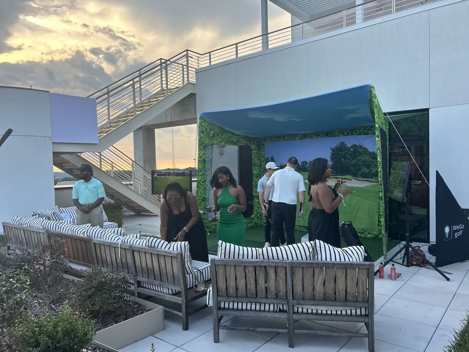 Guests gathered around a WeGo Golf bay on a rooftop lounge at golden hour